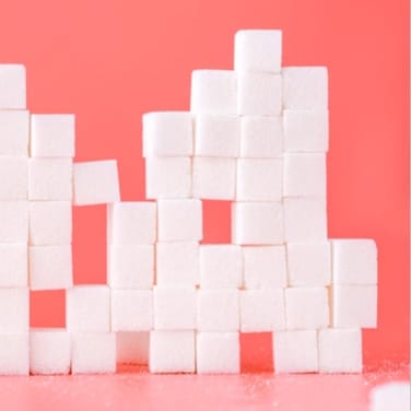 White sugar cubes stacked on top of each other with pink background