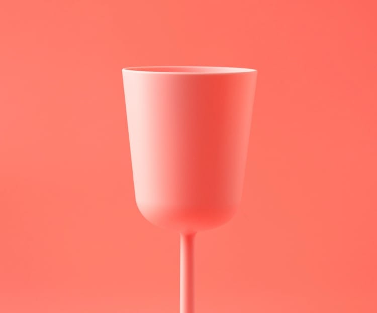 A pink cup in front of a pink background
